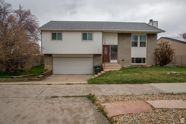 6100 W 3725 S, West Valley City, UT 84128 - raised ranch with fence, an attached garage, concrete driveway, a front yard, and brick siding