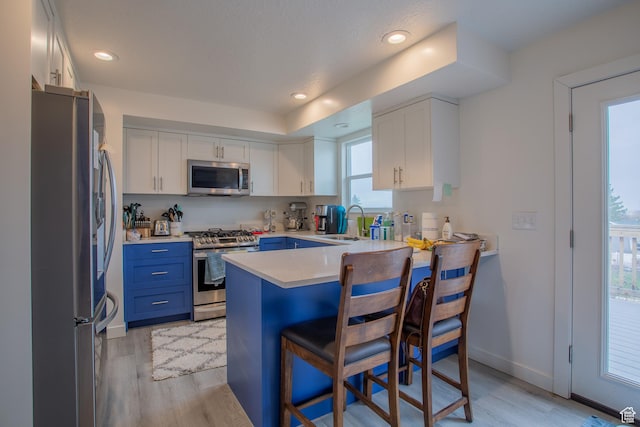 6100 W 3725 S, West Valley City, UT 84128 - kitchen with a kitchen breakfast bar, blue cabinets, a sink, white cabinets, and appliances with stainless steel finishes
