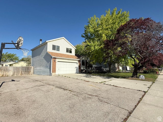 view of side of home with aphalt driveway, fence, and a garage