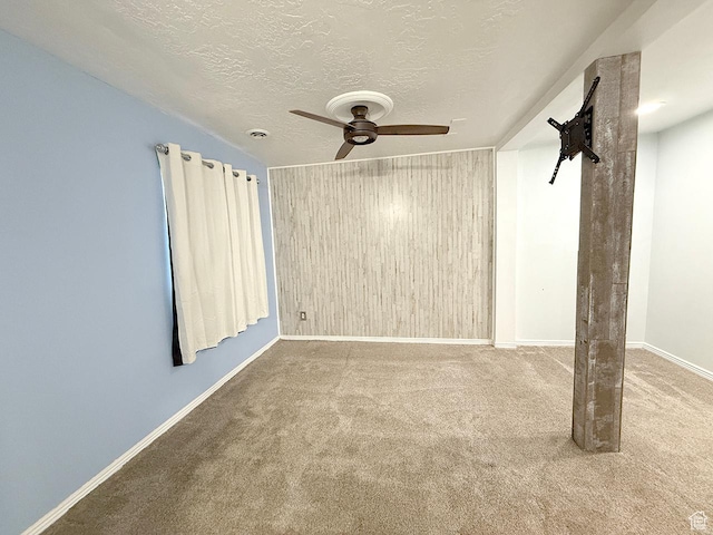 spare room with baseboards, carpet, a textured ceiling, and ceiling fan