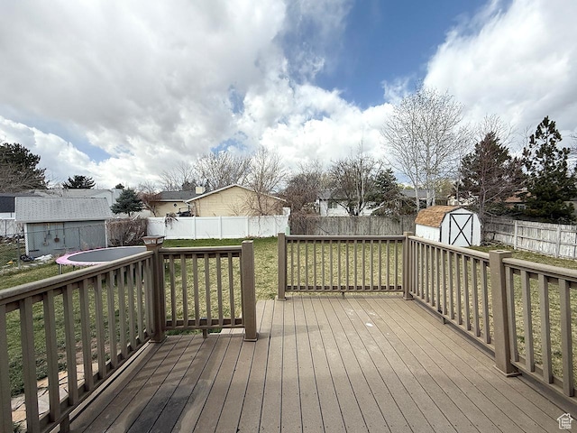 wooden deck with a yard, an outbuilding, a shed, and a fenced backyard
