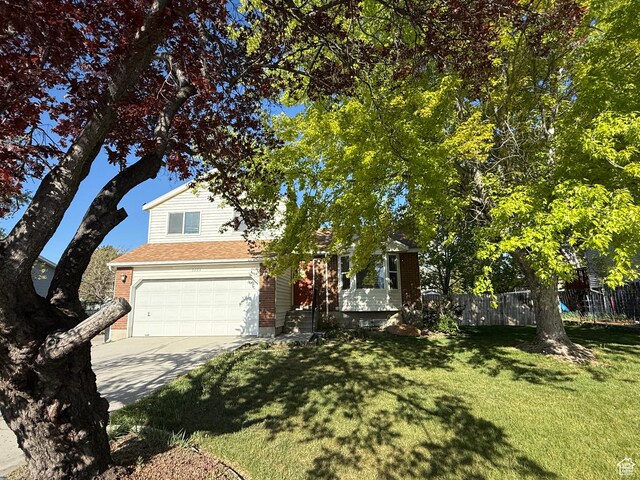 9294 S Vista W Dr W, West Jordan, UT 84088 - view of property hidden behind natural elements featuring concrete driveway, a garage, fence, and a front lawn