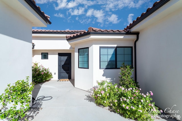 3169 S Pecos Dr, Washington, UT 84780 - property entrance featuring a tiled roof, stucco siding, and a patio area