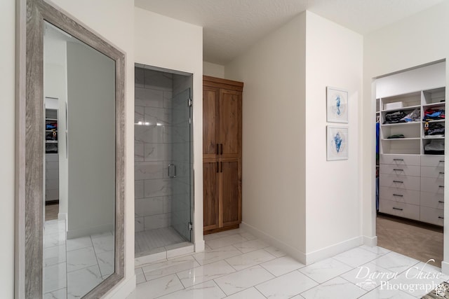 3169 S Pecos Dr, Washington, UT 84780 - full bath with a stall shower, a walk in closet, a textured ceiling, marble finish floor, and baseboards