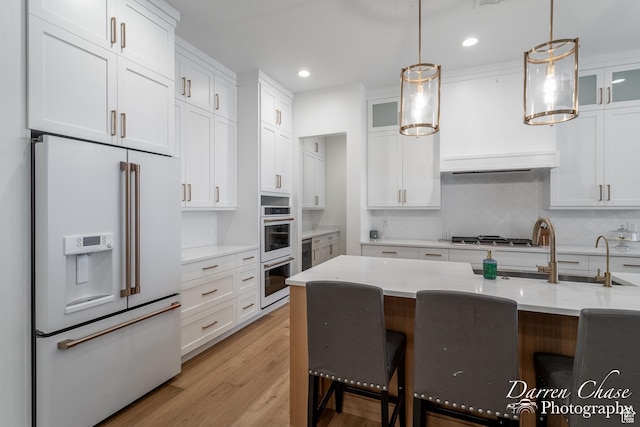 3169 S Pecos Dr, Washington, UT 84780 - kitchen featuring white appliances, white cabinetry, light wood-style flooring, and a breakfast bar