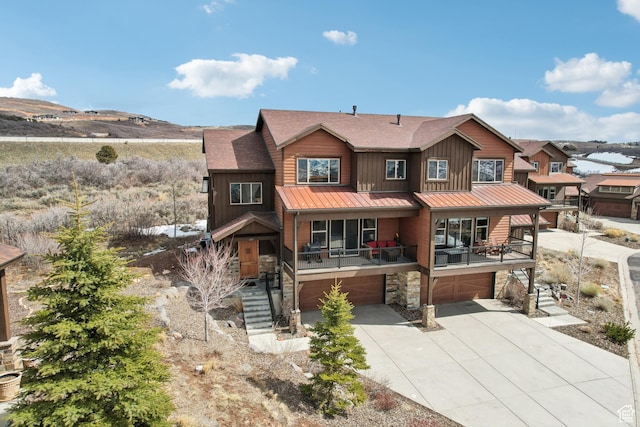 view of front of property featuring metal roof, a garage, stairway, a standing seam roof, and driveway