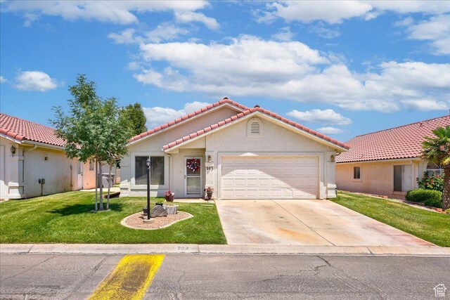mediterranean / spanish home with a tiled roof, a garage, concrete driveway, a front lawn, and stucco siding