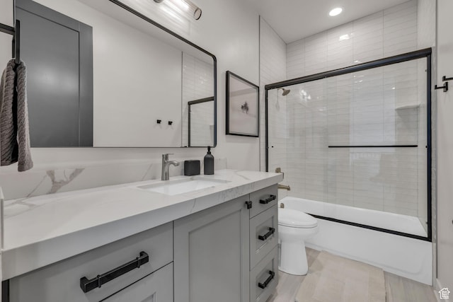 full bathroom with toilet, vanity, and bath / shower combo with glass door