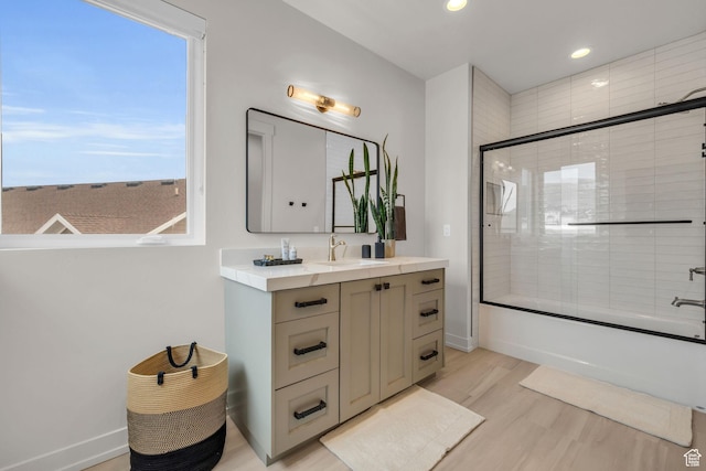 full bathroom featuring baseboards, combined bath / shower with glass door, wood finished floors, recessed lighting, and vanity