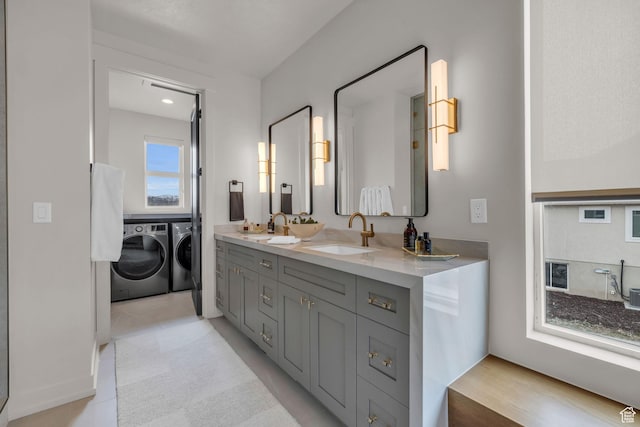 full bathroom featuring double vanity, washing machine and dryer, and a sink