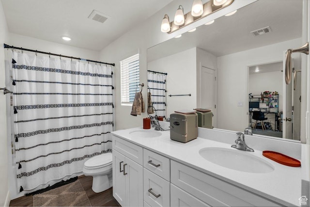 bathroom with toilet, a sink, double vanity, and visible vents