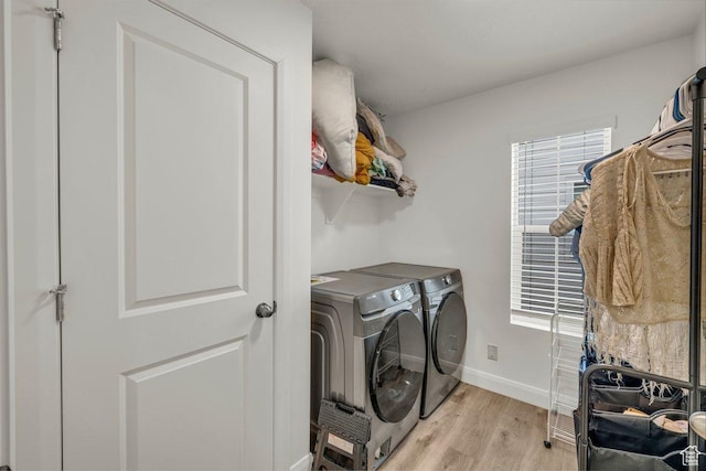 clothes washing area with light wood finished floors, a wealth of natural light, washer and dryer, and laundry area