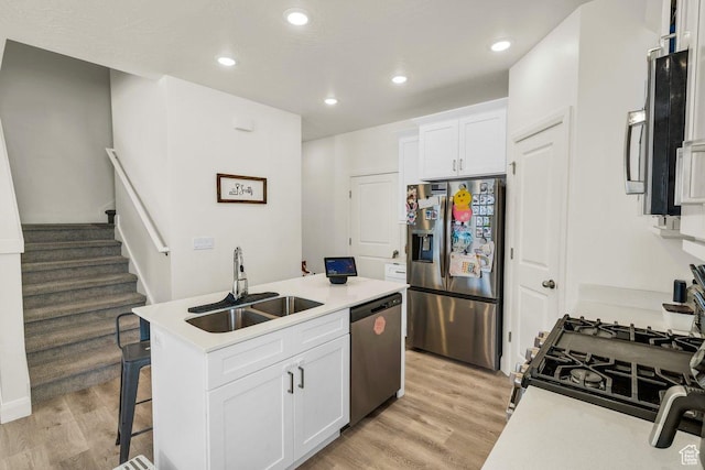 kitchen with a center island with sink, light wood-style floors, a sink, and stainless steel appliances