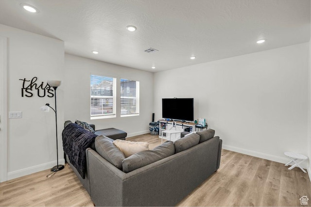 living room with baseboards, visible vents, and light wood finished floors