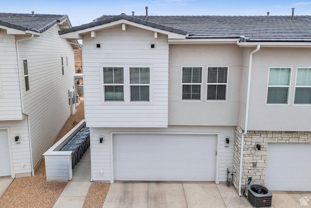 view of front of home featuring stucco siding, a garage, central AC unit, and concrete driveway