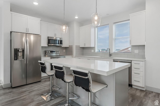 kitchen featuring white cabinetry, a sink, a center island, and appliances with stainless steel finishes