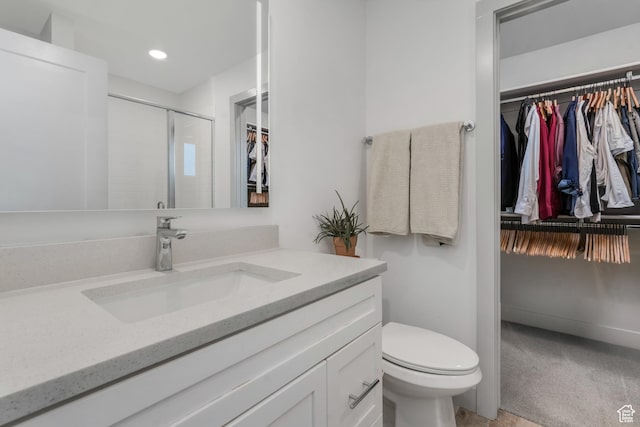 bathroom with vanity, recessed lighting, a spacious closet, toilet, and a stall shower