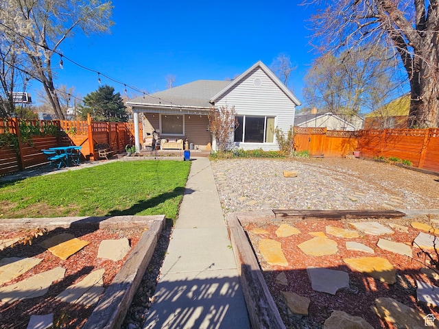 rear view of house with a lawn, a fenced backyard, and a patio area