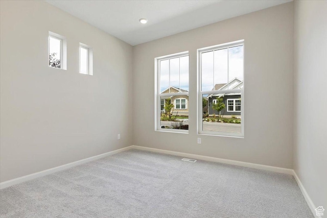 carpeted empty room featuring baseboards and visible vents