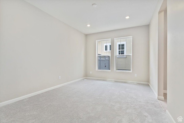 spare room featuring baseboards, recessed lighting, and light carpet
