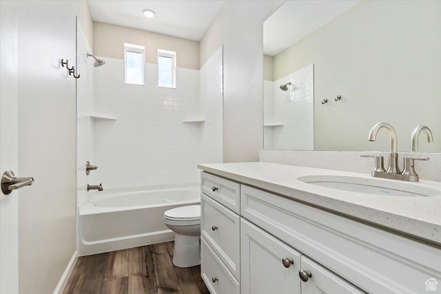full bathroom with washtub / shower combination, baseboards, toilet, wood finished floors, and vanity