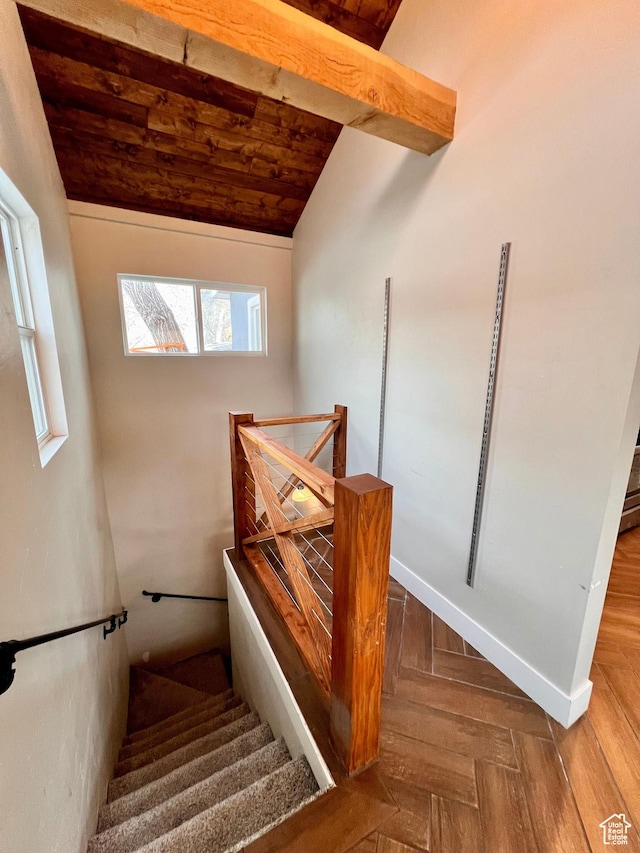 staircase featuring baseboards, vaulted ceiling with beams, parquet floors, and wood ceiling