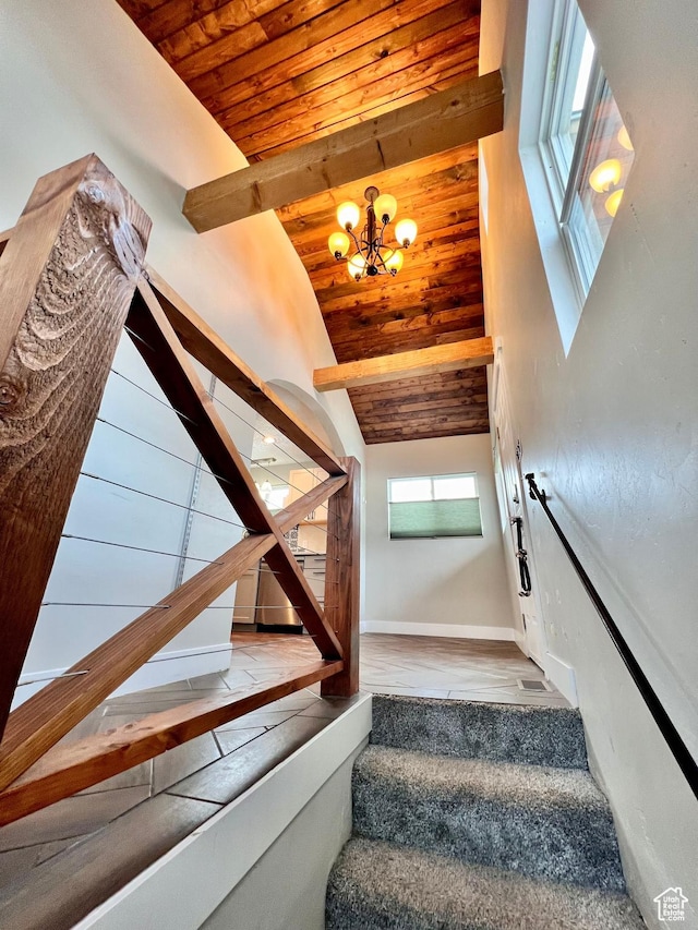 staircase with wood ceiling, a notable chandelier, high vaulted ceiling, and baseboards
