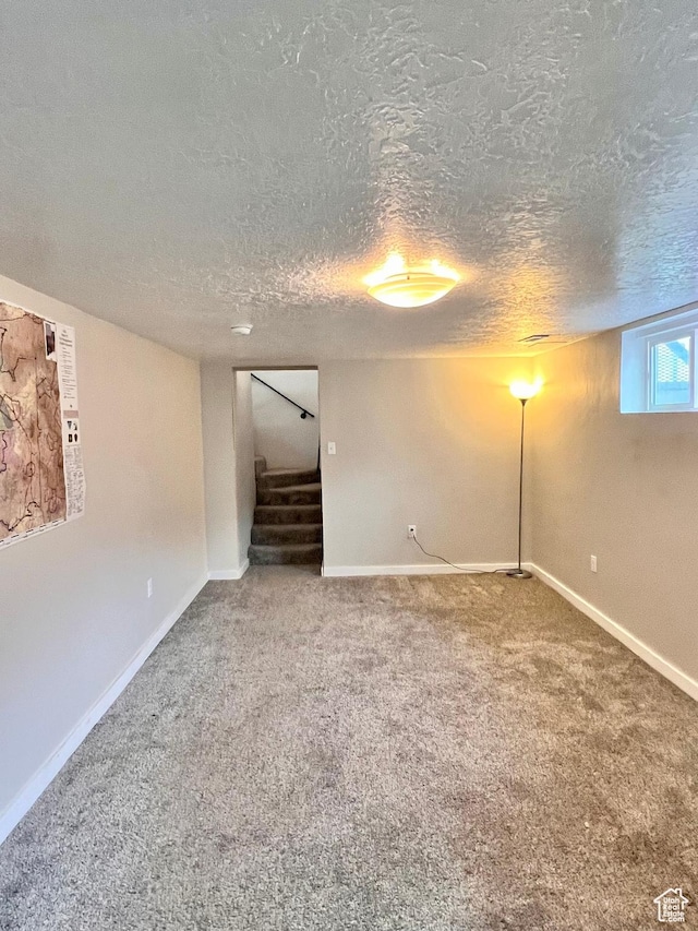 basement featuring carpet floors, baseboards, stairway, and a textured ceiling