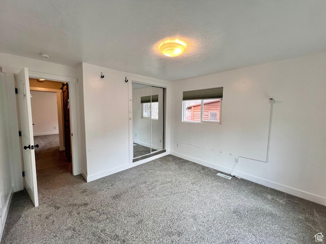 unfurnished bedroom with carpet floors, a closet, baseboards, and a textured ceiling