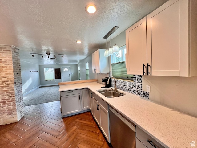 kitchen with a healthy amount of sunlight, open floor plan, a sink, and dishwasher