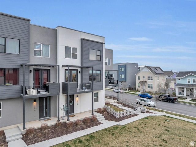 view of front of house featuring a balcony, a residential view, stucco siding, and a porch