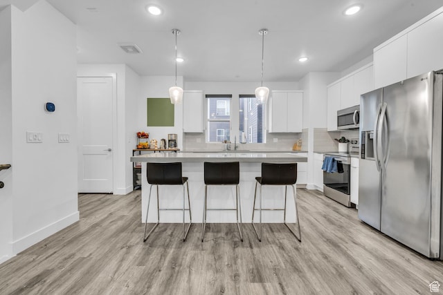 kitchen featuring white cabinetry, tasteful backsplash, a breakfast bar, appliances with stainless steel finishes, and visible vents