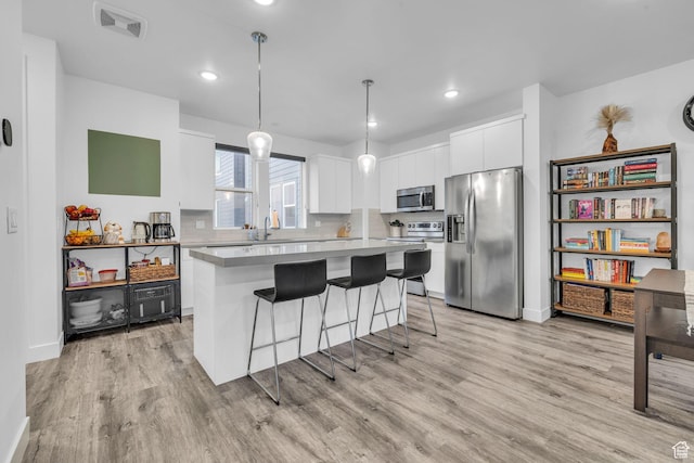 kitchen with a sink, a center island, light wood-type flooring, stainless steel appliances, and white cabinets
