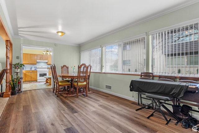 dining space with visible vents, baseboards, ornamental molding, light wood-type flooring, and a notable chandelier