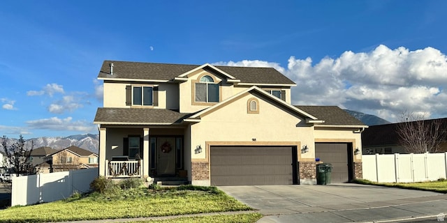 traditional home featuring fence, a garage, concrete driveway, stucco siding, and a mountain view