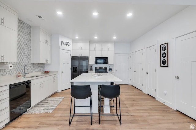 2740 E Kistler Aly, Eagle Mountain, UT 84005 - kitchen with a kitchen bar, tasteful backsplash, a sink, white cabinets, and black appliances
