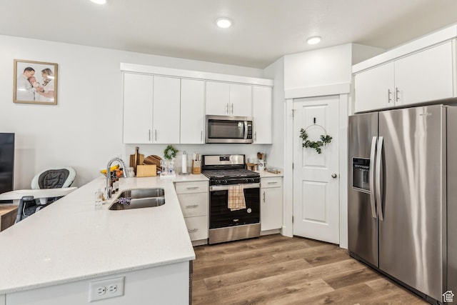 917 W 1000 N Unit 6, Tremonton, UT 84337 - kitchen with white cabinets, wood finished floors, a sink, a peninsula, and appliances with stainless steel finishes