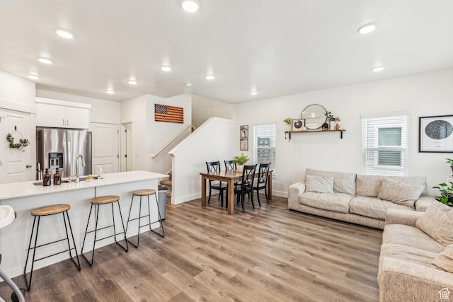 living area featuring recessed lighting, stairs, and light wood-type flooring