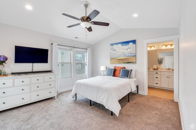 bedroom featuring ensuite bathroom, baseboards, lofted ceiling, a sink, and light colored carpet