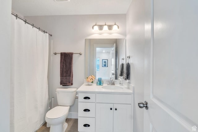 bathroom with toilet, vanity, visible vents, and wood finished floors