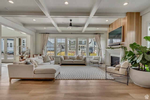living room with beam ceiling, a ceiling fan, a glass covered fireplace, and light wood finished floors