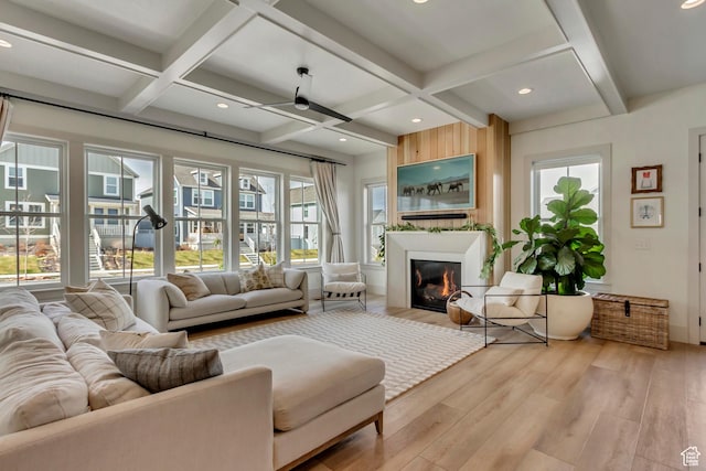 living room with coffered ceiling, a glass covered fireplace, beamed ceiling, light wood-style floors, and recessed lighting
