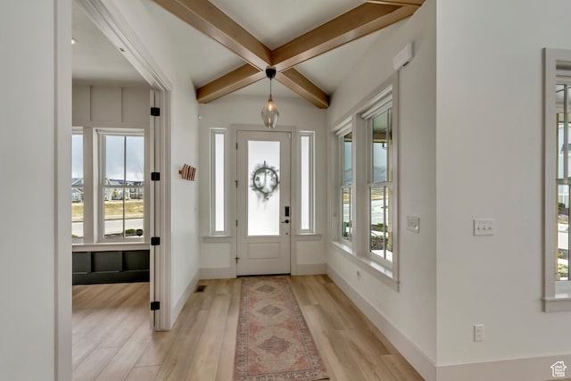 entrance foyer featuring baseboards, a wealth of natural light, light wood-type flooring, and beam ceiling