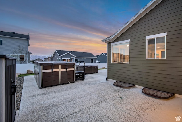 patio terrace at dusk with fence and a hot tub