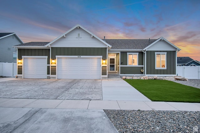ranch-style home featuring fence, an attached garage, concrete driveway, board and batten siding, and a lawn