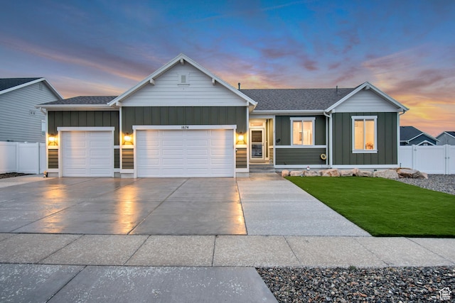 ranch-style house featuring concrete driveway, fence, an attached garage, board and batten siding, and a yard