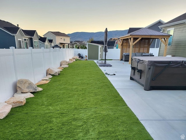 view of yard with an outbuilding, a hot tub, a fenced backyard, a mountain view, and a gazebo