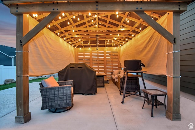 patio terrace at dusk featuring outdoor lounge area, fence, and grilling area