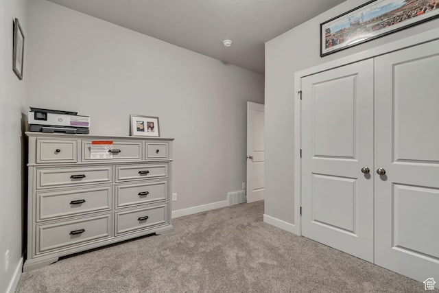 unfurnished bedroom with a closet, baseboards, visible vents, and light carpet