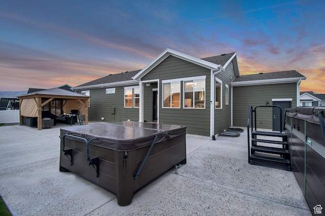 back of property featuring a gazebo, a hot tub, and a patio area